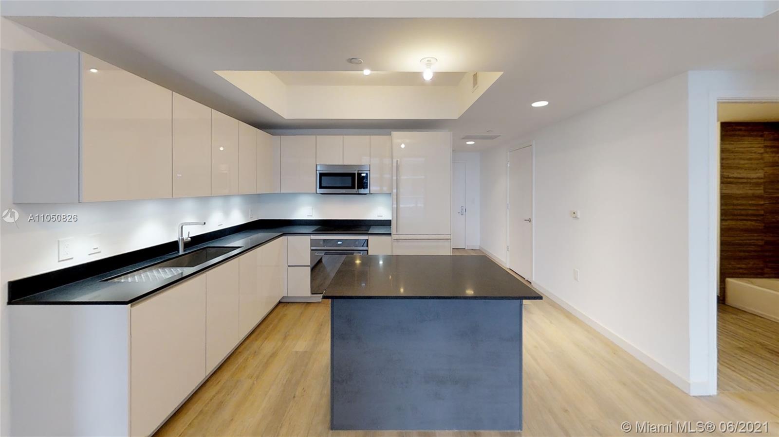 1010 Brickell Avenue, Unit 3209 Miami, FL 33131 - Photo 1 of 31 a kitchen with kitchen island granite countertop a sink a stove and cabinets