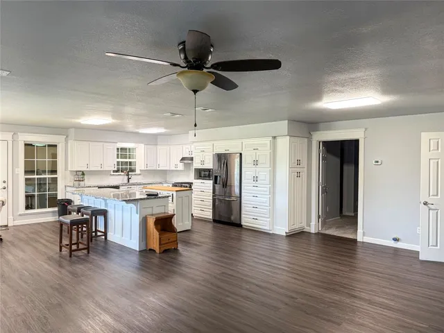 a view of a kitchen with stainless steel appliances wooden floor dining table and chairs