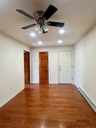 a view of an empty room with window and wooden floor