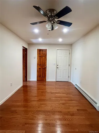 a view of an empty room with window and wooden floor