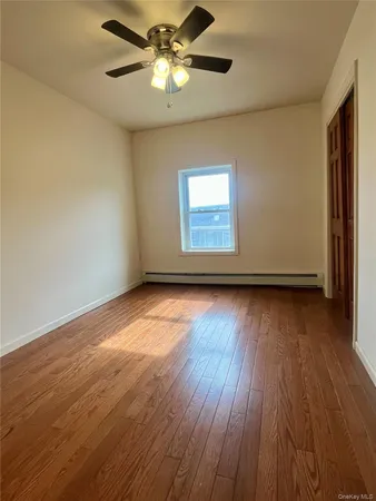 an empty room with wooden floor chandelier fan and windows