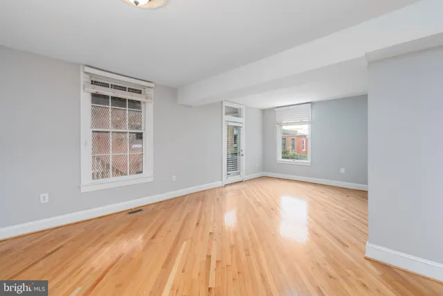 a view of empty room with wooden floor and fan