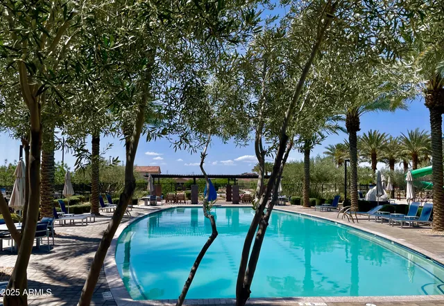 a view of a swimming pool with red chairs under an umbrella