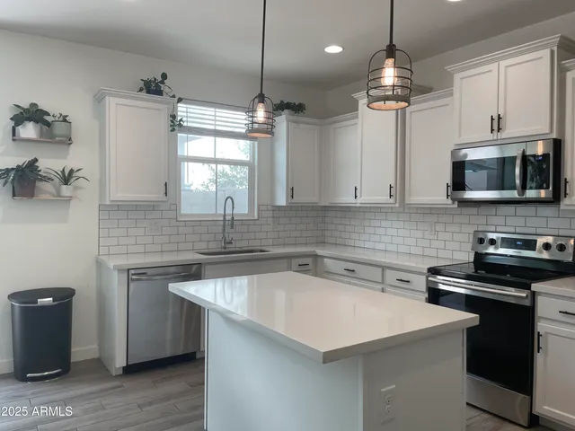 a kitchen that has a sink a microwave oven a stove and white cabinets with wooden floor