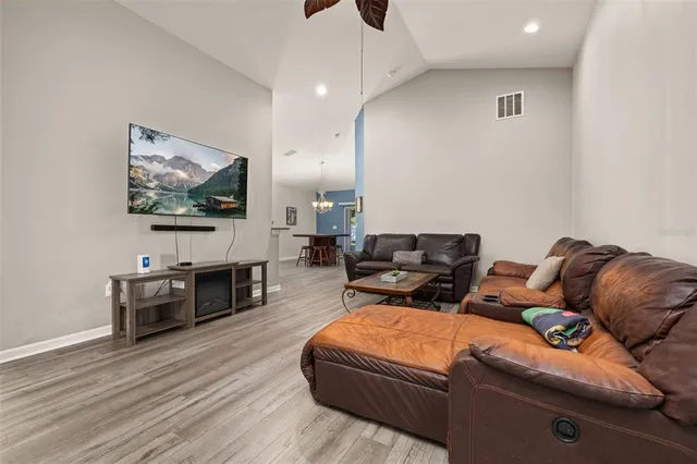 a dining room with wooden floor a chandelier a wooden table and chairs