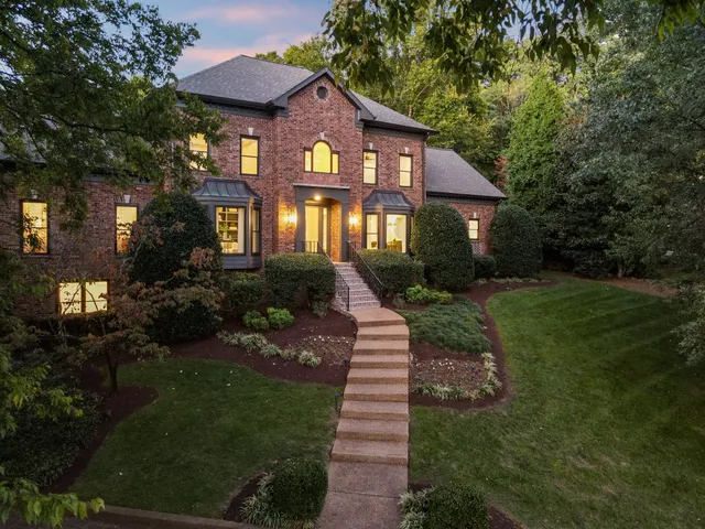 a front view of a house with a yard and green space