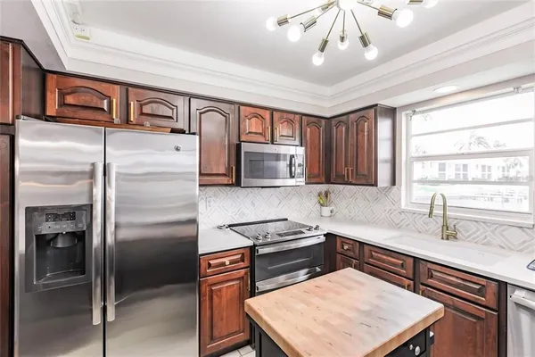 a kitchen with stainless steel appliances granite countertop a refrigerator a sink dishwasher a stove and white countertops with wooden floor