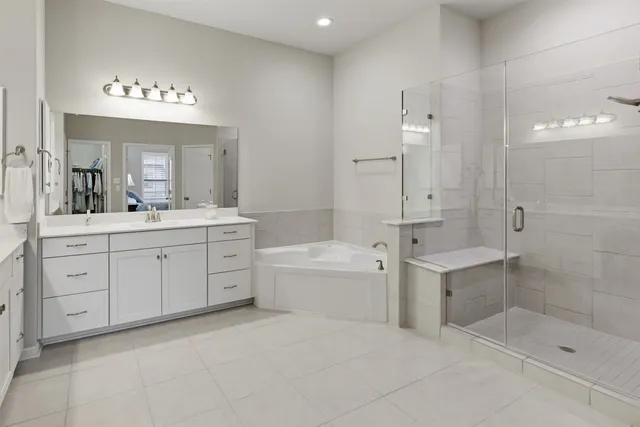 a spacious bathroom with a double vanity sink a large mirror and shower
