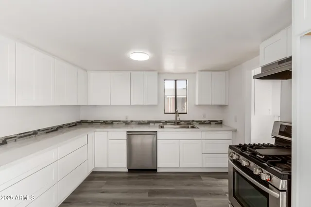 a kitchen with stainless steel appliances granite countertop a stove and white cabinets