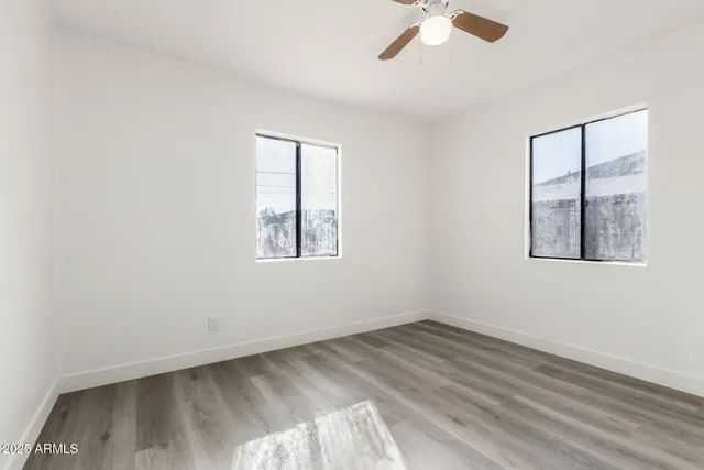 an empty room with a window and ceiling fan