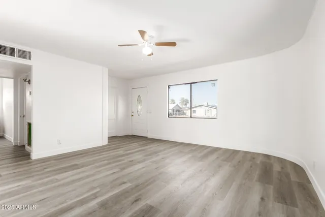 an empty room with wooden floor chandelier and windows