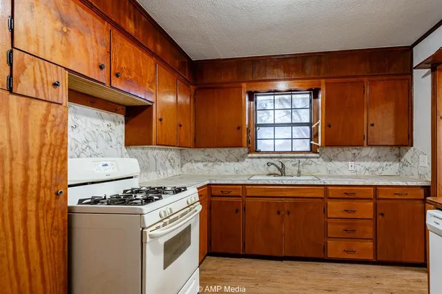 a kitchen with granite countertop a sink cabinets and stainless steel appliances