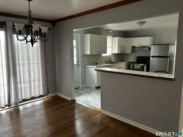 a kitchen with stainless steel appliances granite countertop a refrigerator a sink dishwasher a stove and white countertops with wooden floor