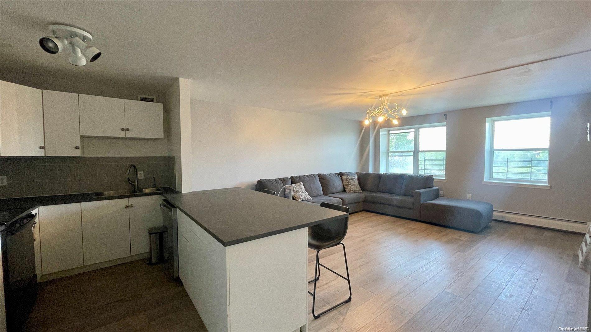 260 Beach 81st Street, Unit 2P Queens, NY 11693 - Photo 1 of 1 a kitchen with a stove a sink and white cabinets with wooden floor
