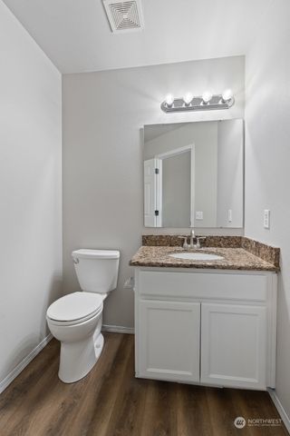 a bathroom with a granite countertop toilet a sink and a mirror