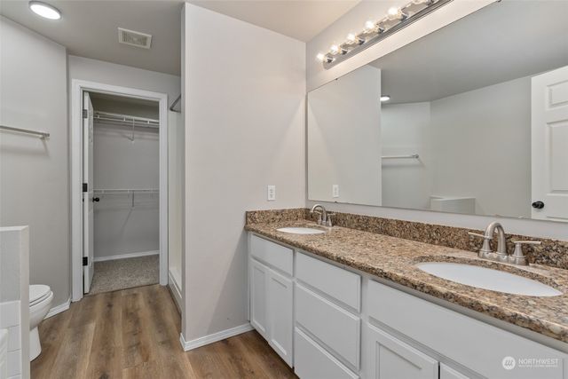 a bathroom with a granite countertop sink a mirror and a toilet