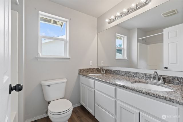 a bathroom with a granite countertop toilet sink and mirror