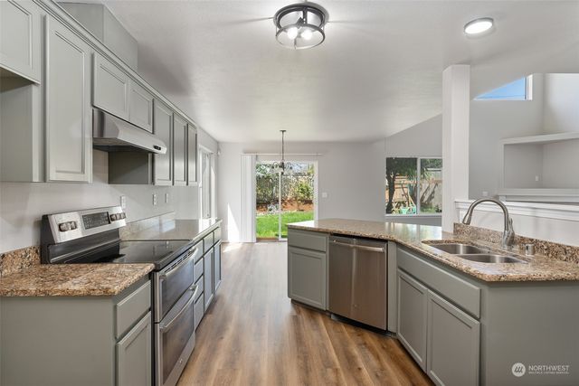 a kitchen with stainless steel appliances granite countertop a sink stove and refrigerator