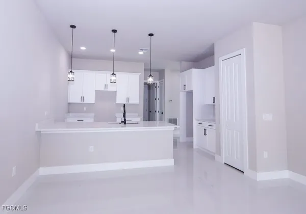 a large white kitchen with kitchen island a sink a stove a refrigerator and white cabinets
