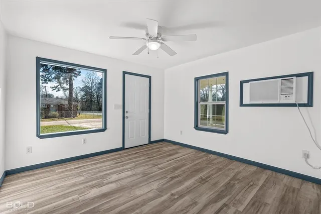 a view of an empty room with a window and wooden floor