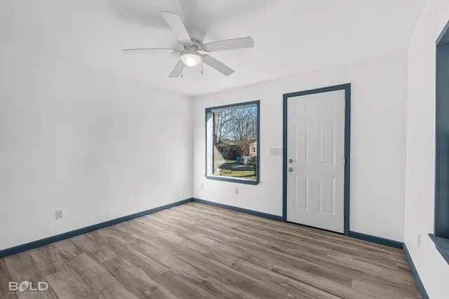 a view of an empty room with wooden floor and a window
