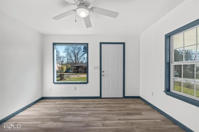 a view of an empty room with a window and wooden floor