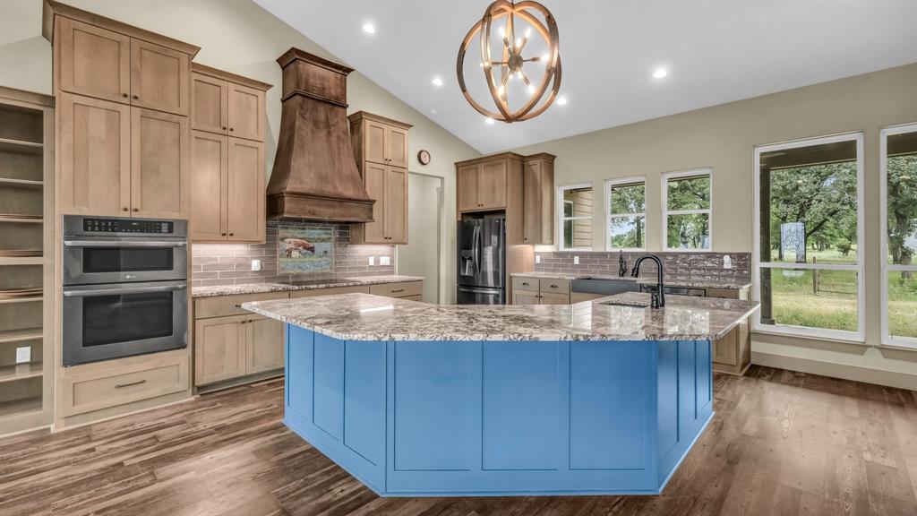 990 Doss Road Millsap, TX 76066 - Photo 19 of 40 a kitchen with kitchen island granite countertop wooden cabinets and a large window