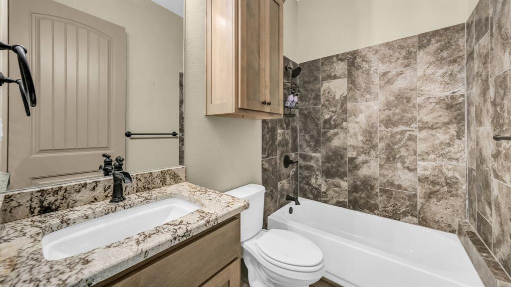 990 Doss Road Millsap, TX 76066 - Photo 27 of 40 a bathroom with a granite countertop bathtub sink vanity mirror and toilet