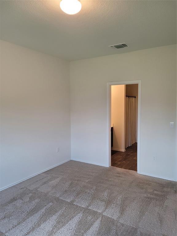 14917 Gypsum Mill Road Manor, TX 78653 - Photo 20 of 28 A well-lit room showcasing plush carpeting and a doorway leading to an adjacent space.