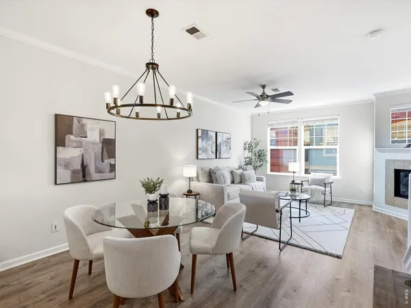 a living room with couches a dining table and a chandelier
