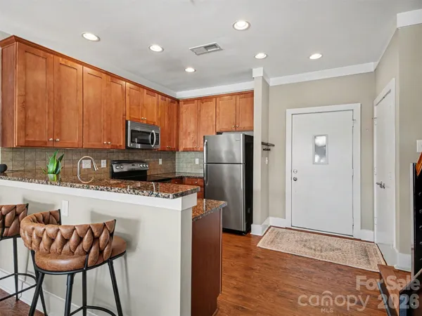 a kitchen with stainless steel appliances granite countertop a refrigerator a stove top oven a sink dishwasher and a refrigerator with wooden floor