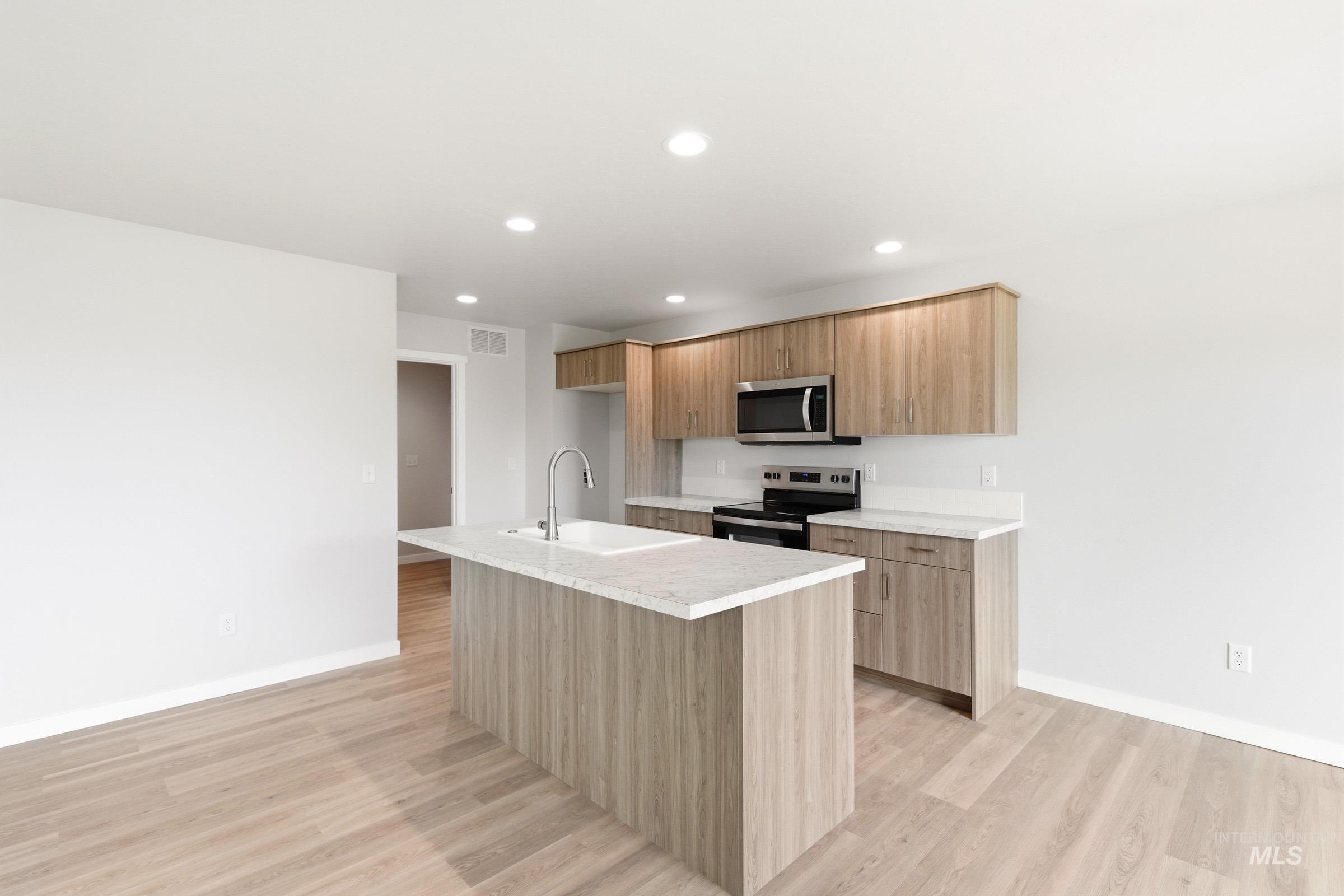 2446 West Fallon Loop Nampa, ID 83651 - Photo 3 of 19 Kitchen with stainless steel appliances, a center island with sink, light wood-style flooring, modern cabinets, and recessed lighting