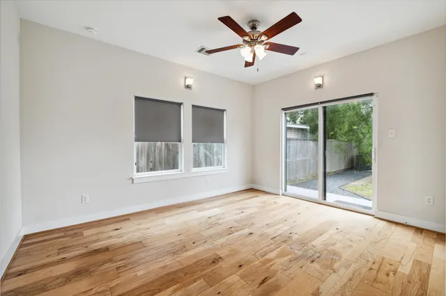a view of an empty room with a window and wooden floor