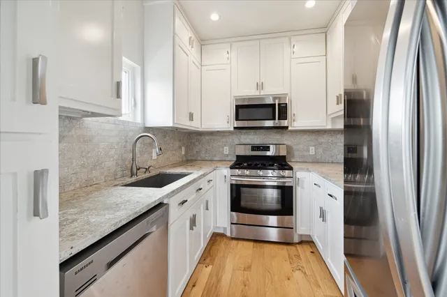 a kitchen with stainless steel appliances granite countertop a sink a stove and a refrigerator
