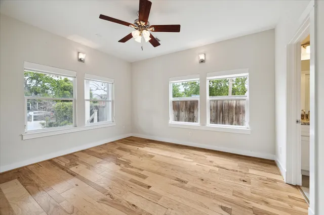 a view of an empty room with a window and wooden floor