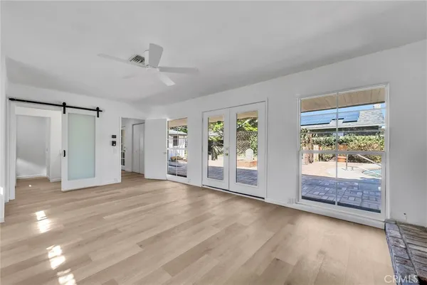 a view of an empty room with window and wooden floor