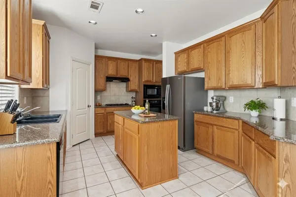 a kitchen with stainless steel appliances granite countertop a stove top oven a refrigerator a sink and dishwasher