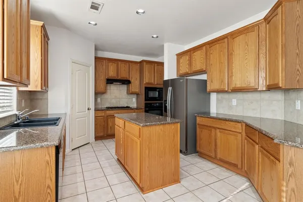a kitchen with stainless steel appliances granite countertop a stove top oven a refrigerator a sink and dishwasher