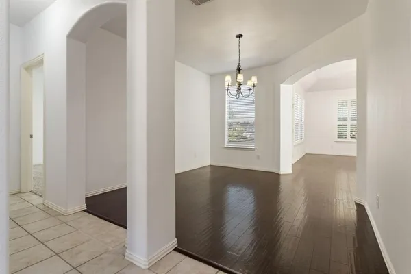 an empty room with wooden floor chandelier and entryway
