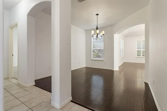 an empty room with wooden floor chandelier and entryway