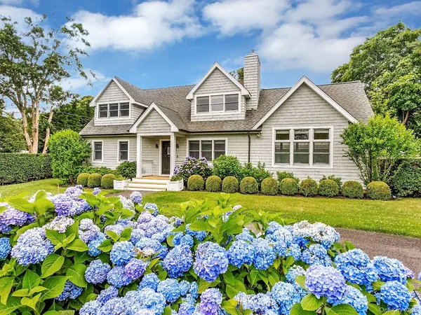 a front view of a house with a big yard and potted plants