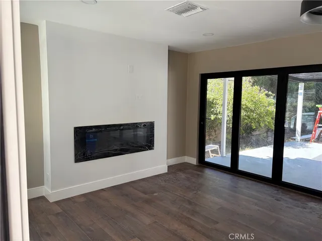 a view of a big room with wooden floor and an entryway