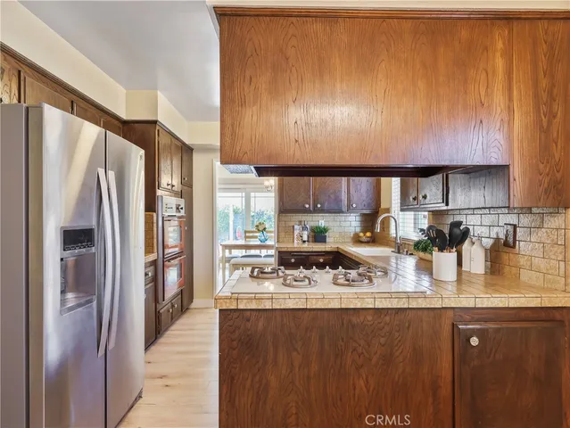 a kitchen with stainless steel appliances granite countertop a refrigerator a stove and a sink with wooden floor