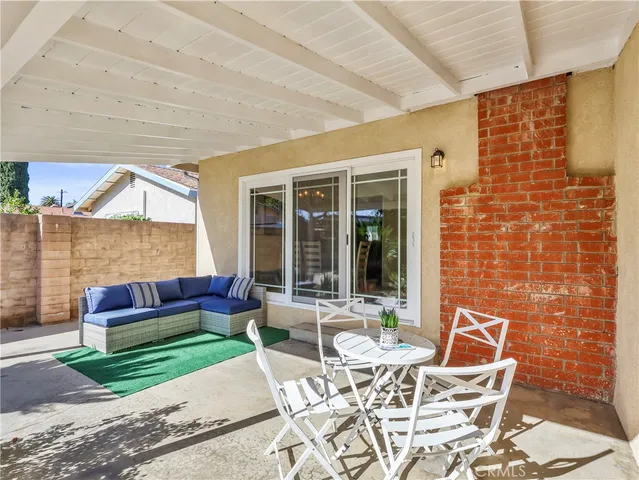 a patio with water table and chairs under an umbrella next to a yard