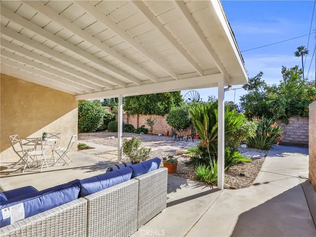a patio with water table and chairs under an umbrella next to a yard