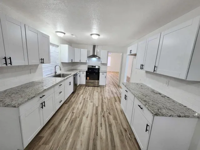 a large kitchen with granite countertop a large counter top stainless steel appliances and cabinets