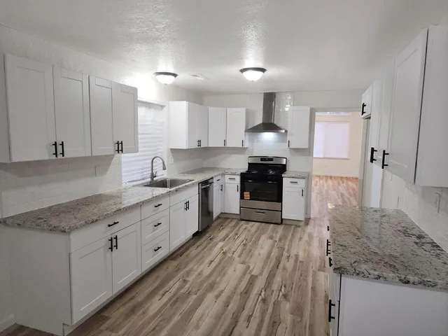 a large kitchen with stainless steel appliances granite countertop a lot of counter space and wooden floors