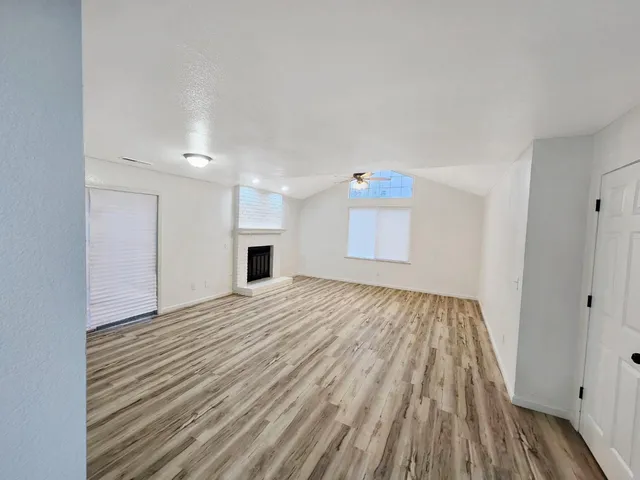 a view of empty room with wooden floor and fireplace