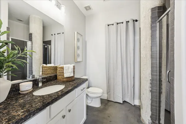 a bathroom with a granite countertop sink and a mirror with toilet