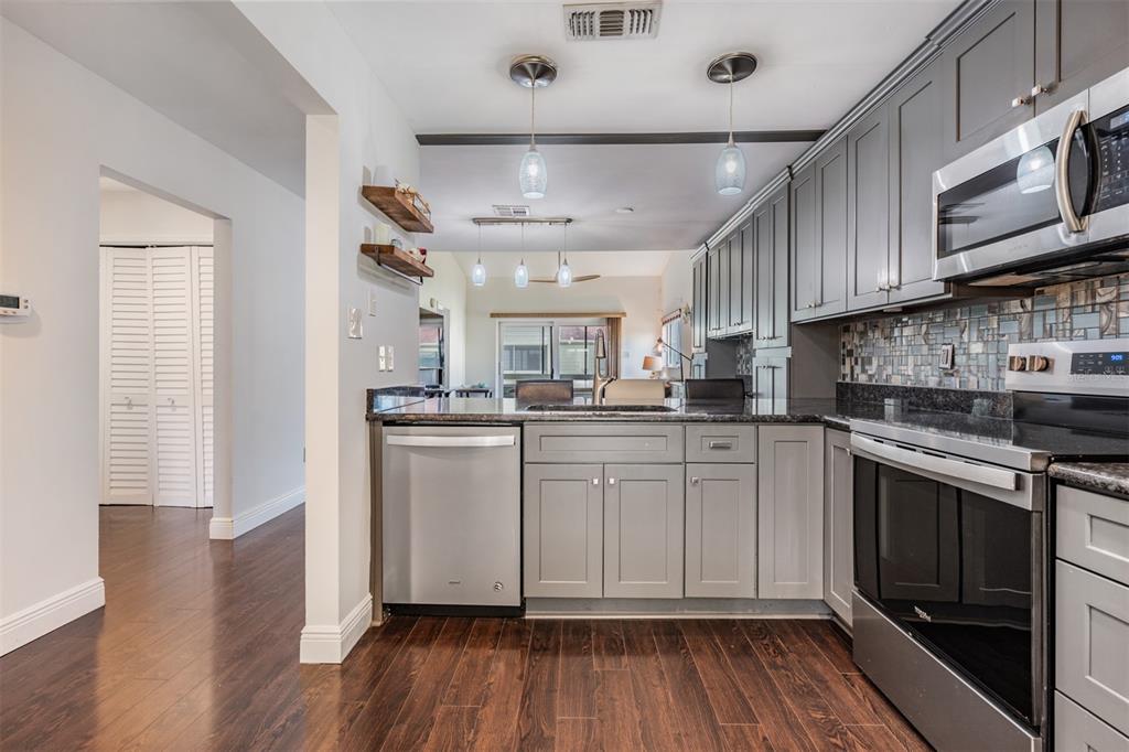 637 Drake Lane North Dunedin, FL 34698 - Photo 7 of 43 a kitchen with stainless steel appliances granite countertop a stove cabinets and wooden floor